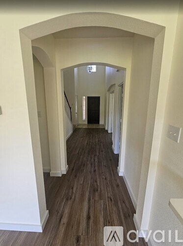 A hallway with wooden floors and white walls.
