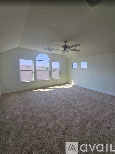 A room with a carpeted floor, a ceiling fan, and a large window with a view of the desert.