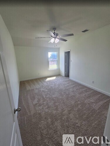 A room with a carpeted floor and a ceiling fan.