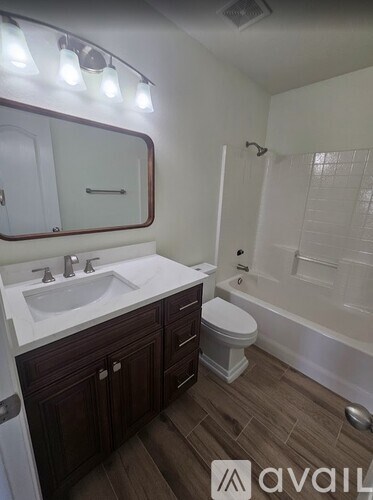 A bathroom with a white sink and brown cabinets.