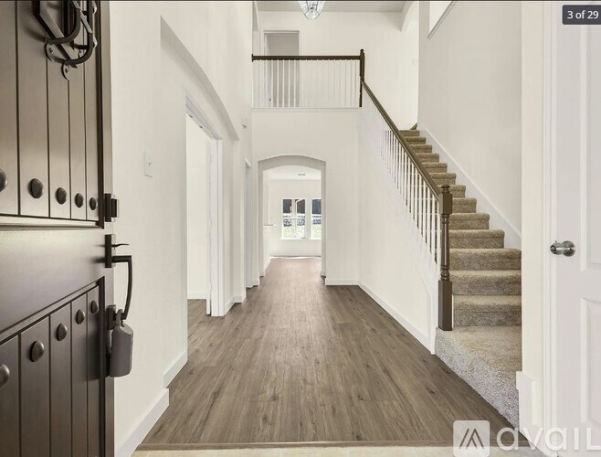 A long hallway with a staircase and a door on the right.