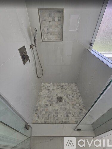 A tiled shower area with a glass door and a shower head.