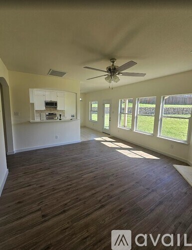 A spacious room with wooden floors and a ceiling fan.