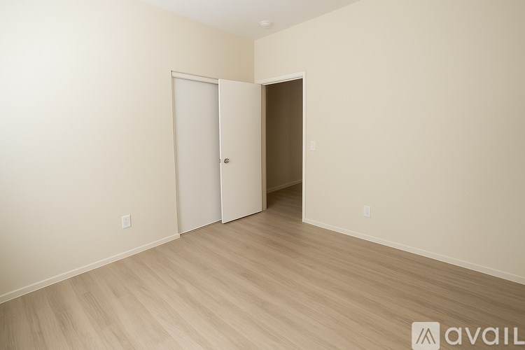 A room with a white door and a brown door with a wooden floor.