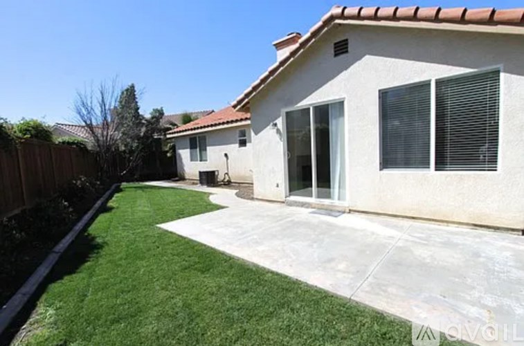 A house with a white exterior and a brown roof has a green lawn in front.