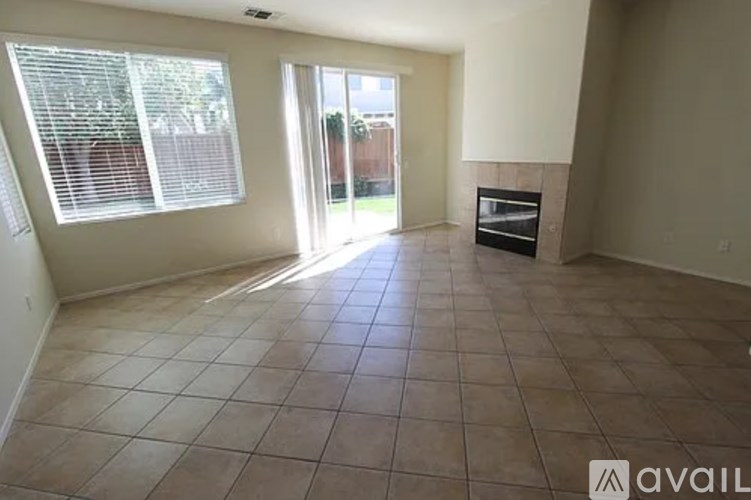 A room with tiled flooring and a large window with blinds.
