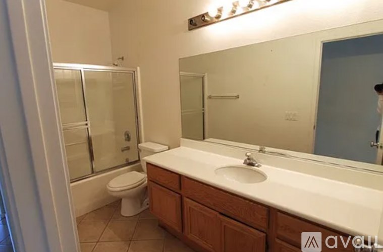 A bathroom with a toilet, sink, and mirror.