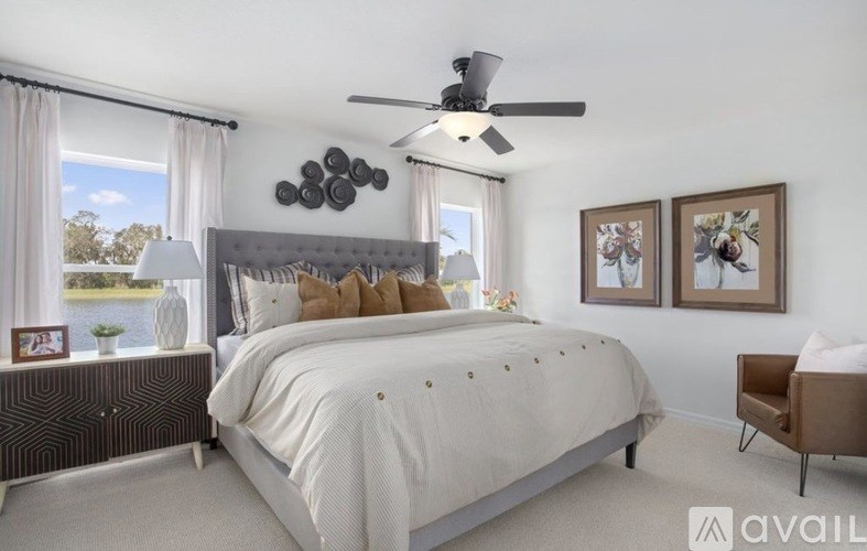 A bedroom with a large bed, a ceiling fan, and a chair.