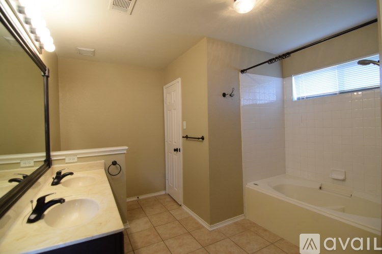 A bathroom with a tub, sink, and mirror.