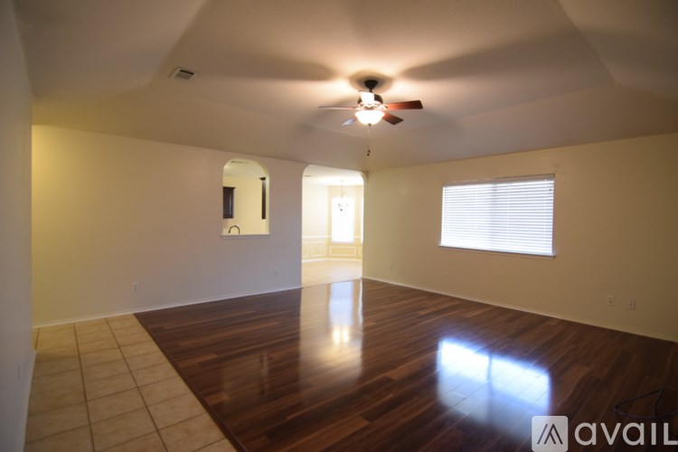 A room with a ceiling fan and a window with blinds.
