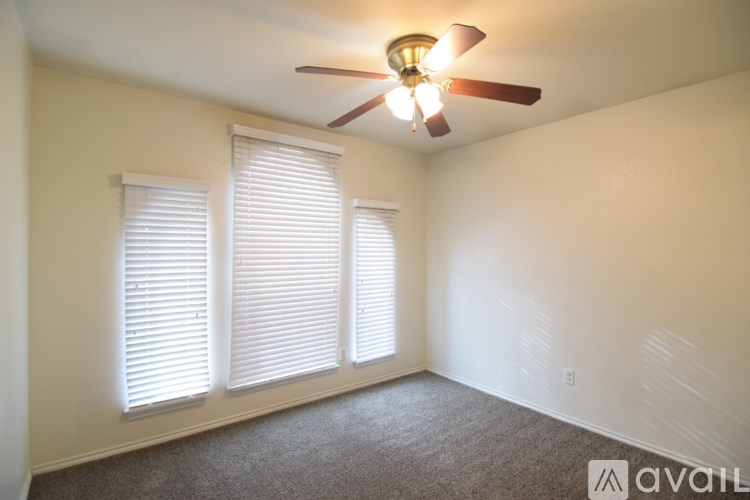 A room with a ceiling fan and two windows with blinds.