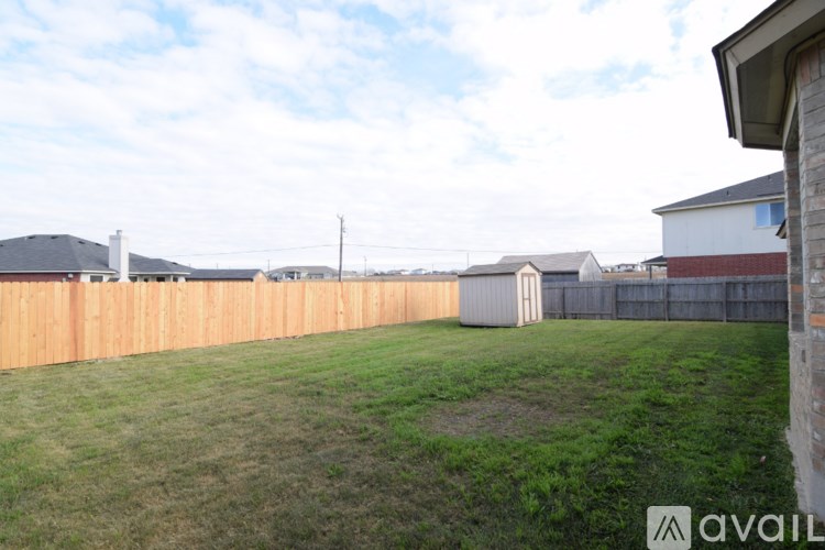 A grassy area with a wooden fence and houses in the background.