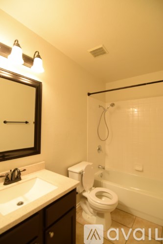 A bathroom with a toilet, sink, and mirror.