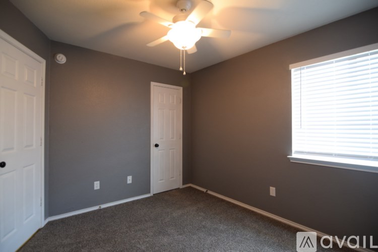 A room with a ceiling fan and two doors.