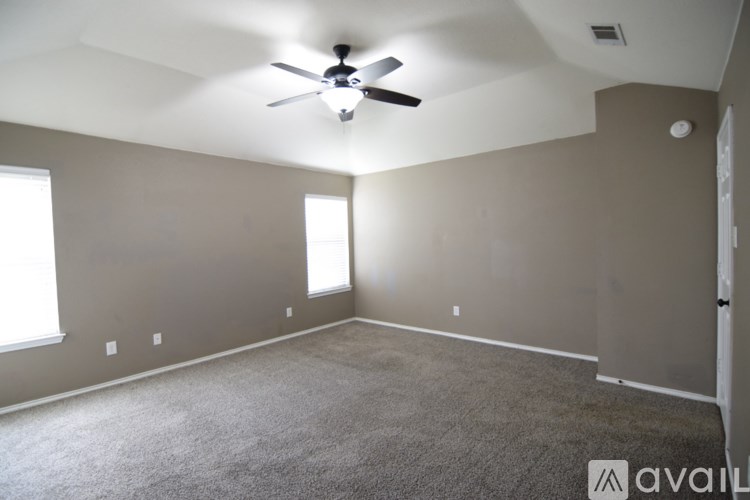 A room with a ceiling fan and carpeted floor.