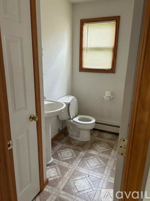 A bathroom with a toilet, sink, and window.