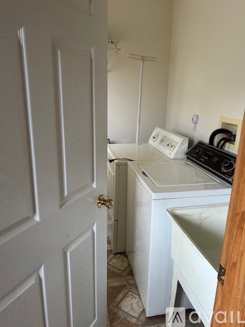 A white washing machine sits in a small laundry room.