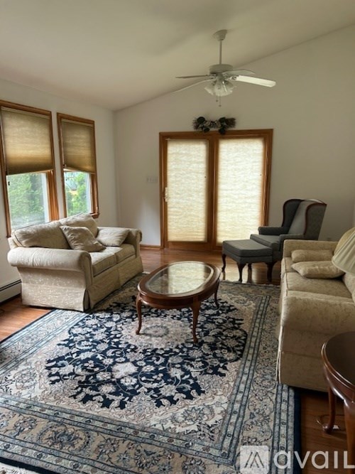 A living room with a rug, a chair, a sofa, and a table.