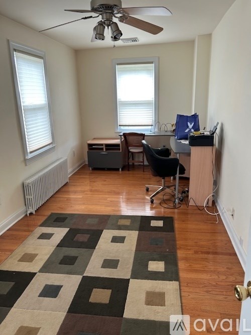 A room with a ceiling fan and a rug on the floor.