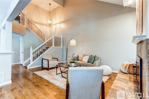 A living room with a grey sofa and a wooden staircase.