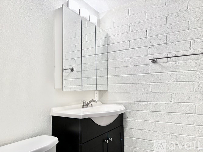 A white bathroom with a black vanity and a white toilet.