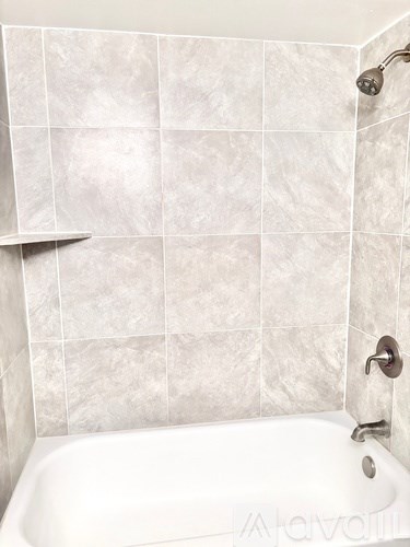 A white bathtub with a shower head above it.