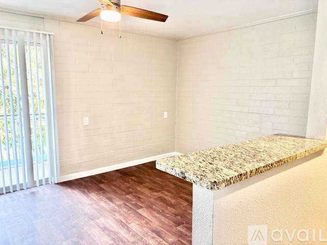 A room with a ceiling fan and a window with blinds.