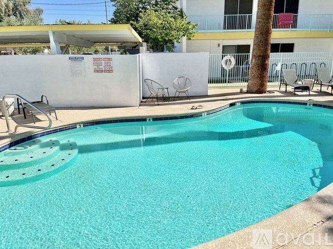 A swimming pool with a white fence and a tree in the background.
