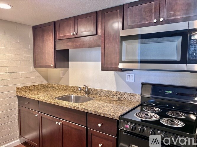 A kitchen with brown cabinets and a granite countertop.