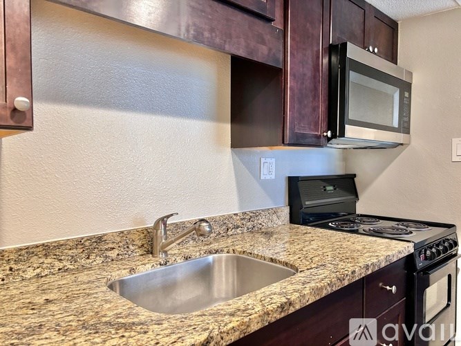 A kitchen with a granite countertop and a black microwave above it.