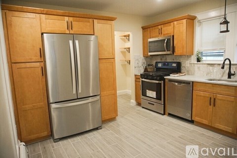 A kitchen with a stainless steel refrigerator and wooden cabinets.