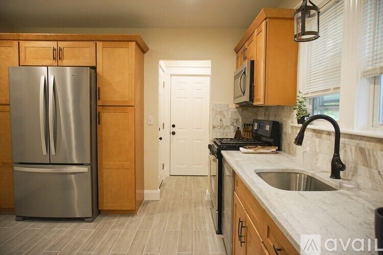 A kitchen with a stainless steel refrigerator and wooden cabinets.