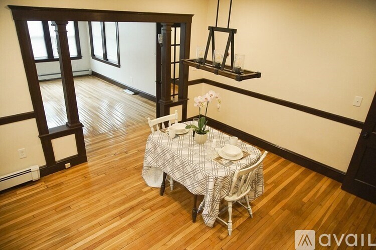 A dining room with a table set for two and a chandelier.