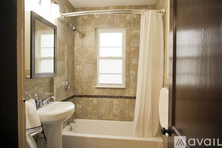 A bathroom with a tub, sink, and mirror.