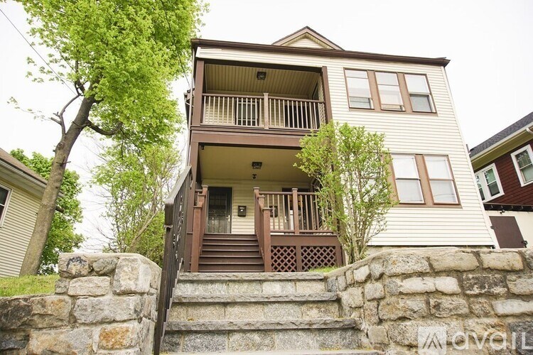 A two-story house with a balcony and a stone wall.