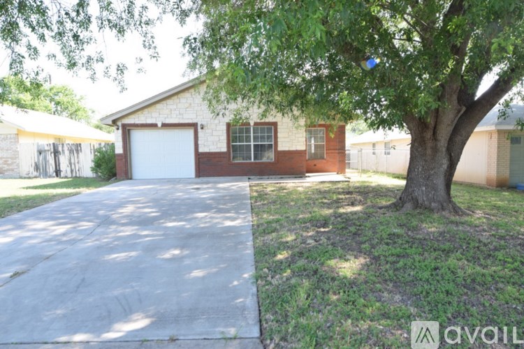 A house with a driveway and a tree in front.