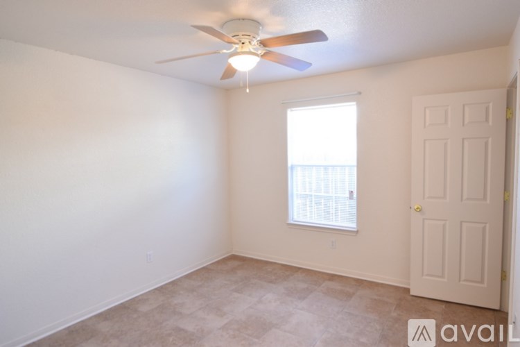 A room with a ceiling fan and a window with a view of a balcony.