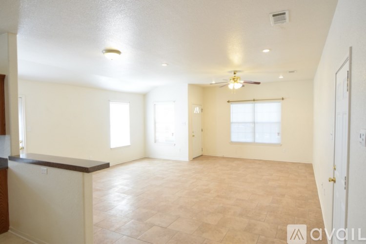 A spacious living room with a ceiling fan and large windows.