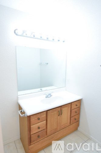 A bathroom with a sink and wooden cabinets.