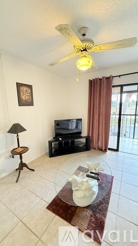 A living room with a television, a floor lamp, and a table with a vase on it.