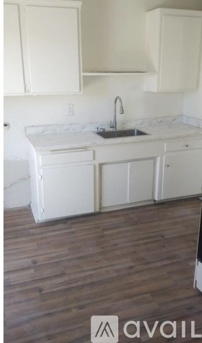 A kitchen with white cabinets and a wooden floor.