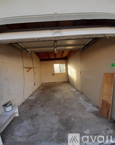 A room with a concrete floor and walls under construction with a window on the right.