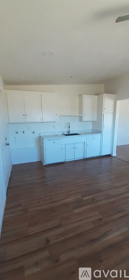 A kitchen with white cabinets and a wooden floor.