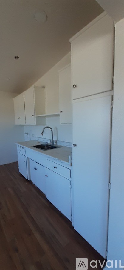 A kitchen with white cabinets and a wooden floor.