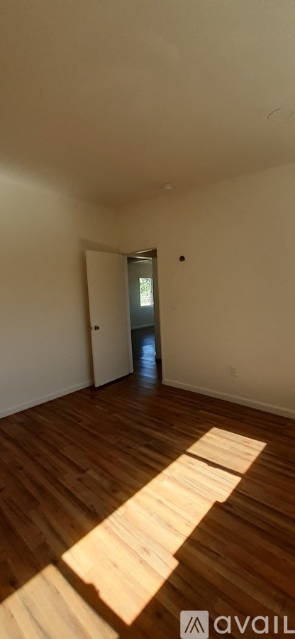 A room with wooden flooring and a doorway leading to another room.