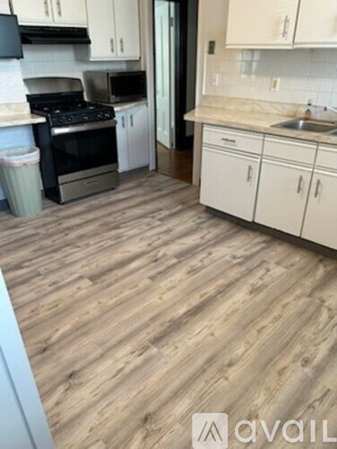 A kitchen with a wooden floor and white cabinets.