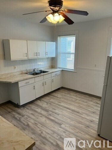 A kitchen with white cabinets and a wooden floor.
