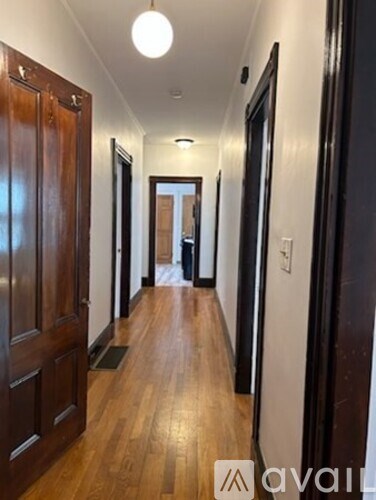 A long hallway with wood floors and dark wood doors.