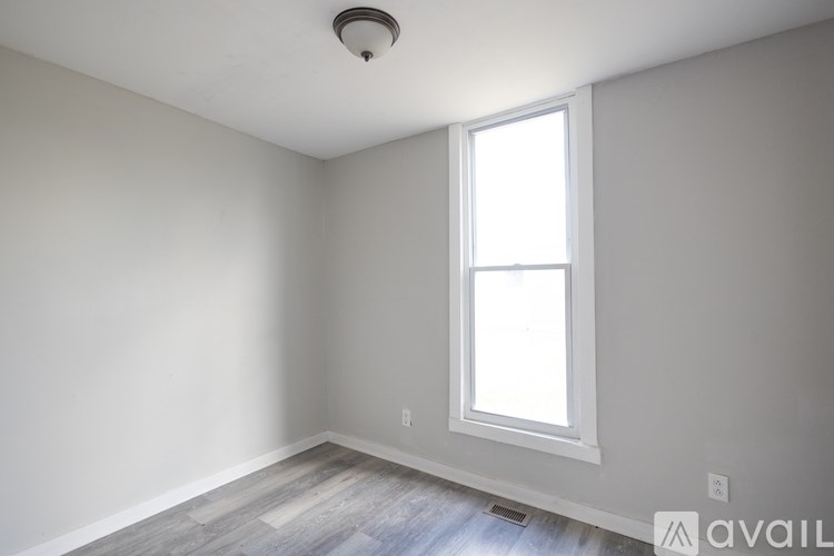 A room with a window and a wooden floor.