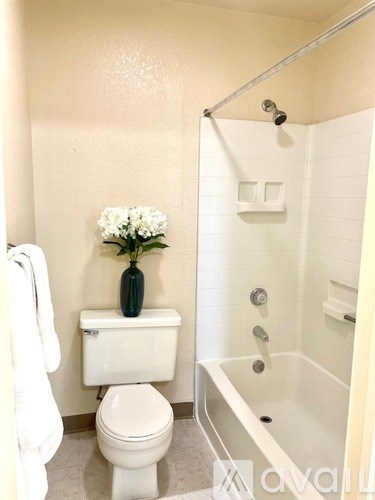 A white toilet sits next to a white bathtub in a bathroom.